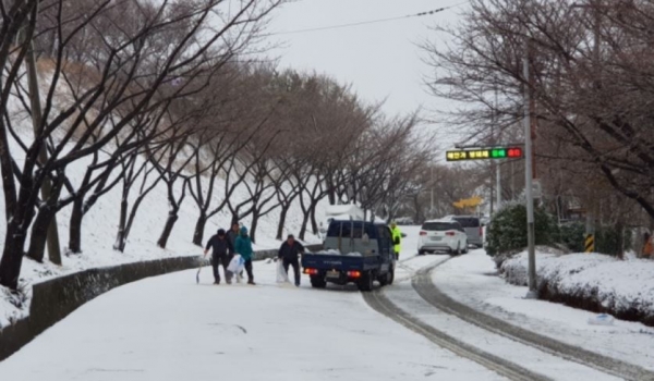 21일 오전 부산 연제구 황령산 주요 도로에 눈이 쌓여 경찰과 관계 당국 공무원이 제설작업을 하고 있다.
