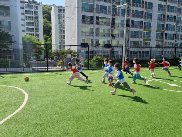 유치원 내 있는 축구장에서 축구를 하는 아이들.